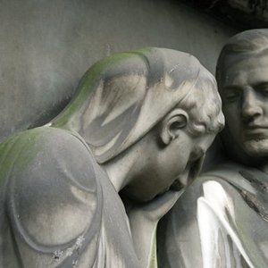 Köpfe von Statuen von Mann und Frau aus grauem Stein, traurig nach unten blickend