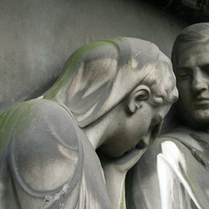 Köpfe von Statuen von Mann und Frau aus grauem Stein, traurig nach unten blickend
