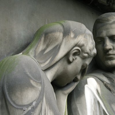 Köpfe von Statuen von Mann und Frau aus grauem Stein, traurig nach unten blickend