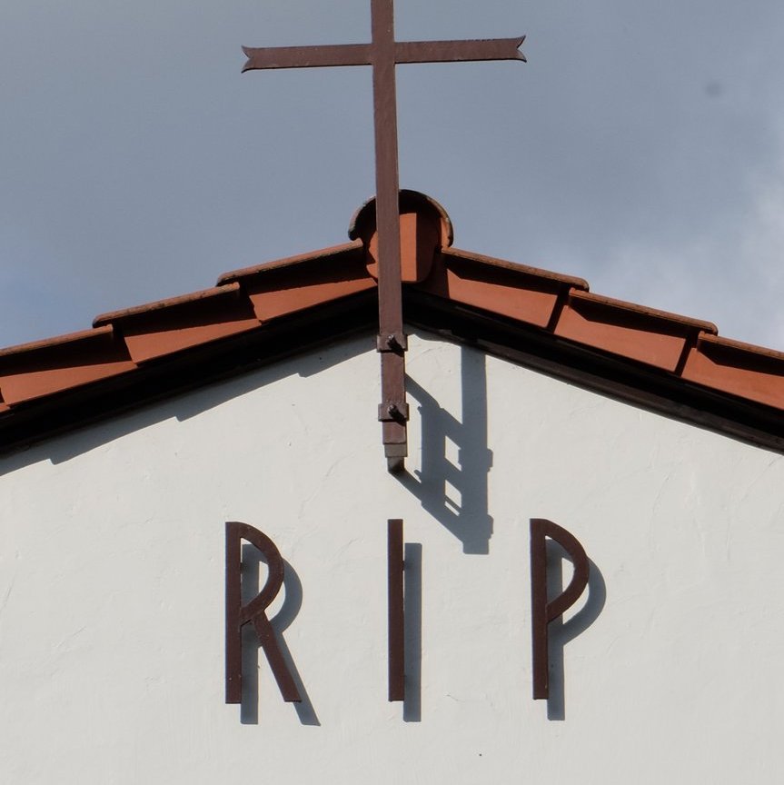 Helle Kapelle mit rotem Dach mit Aufschrift RIP