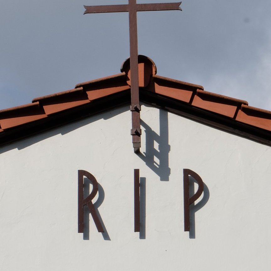 Helle Kapelle mit rotem Dach mit Aufschrift RIP