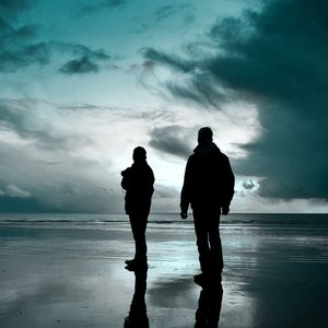 Zwei Menschen stehen bei wolkigem Himmel am Meer