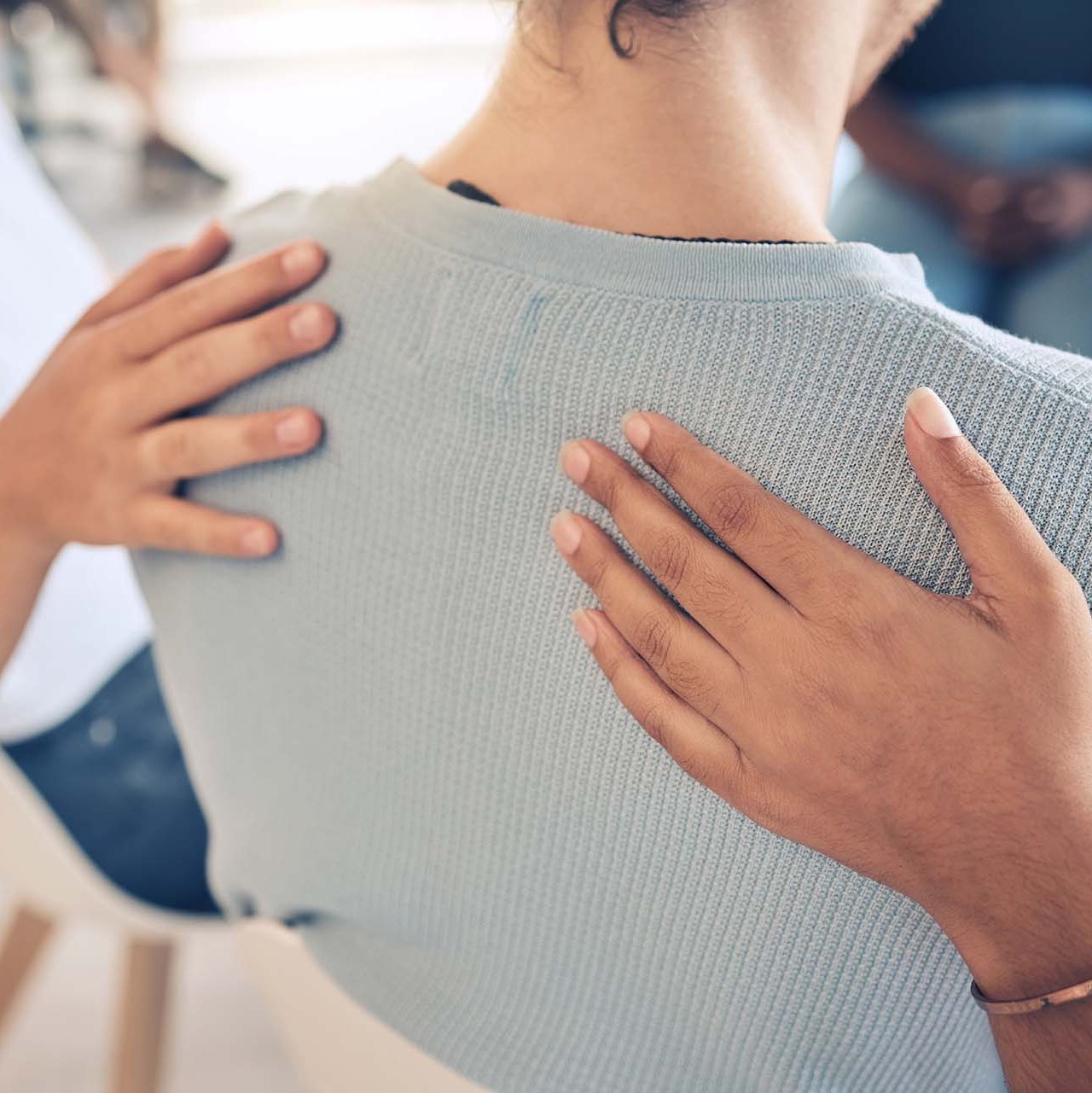 Zwei Personen legen einer Frau ihre Hände auf den Rücken