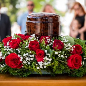 Urne mit Blumenkranz bei einer Trauerfeier