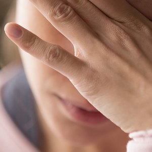 Frau fasst sich an die Stirn und bedeckt ihre Augen