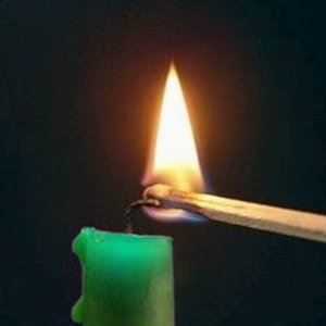 Grüne Kerze wird mit Streichholz angezündet